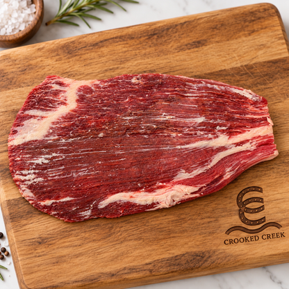 Akaushi flank steak laid horizontally on a Crooked Creek wooden cutting board